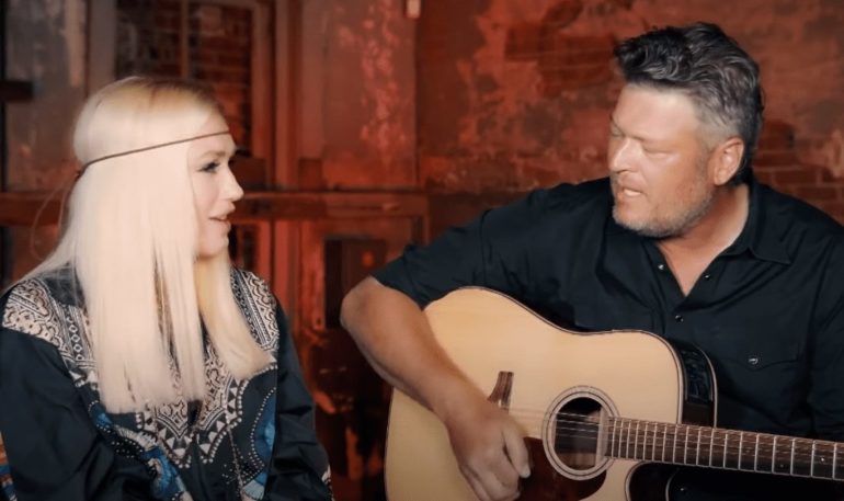 Blake Shelton playing a guitar next to a woman playing a guitar