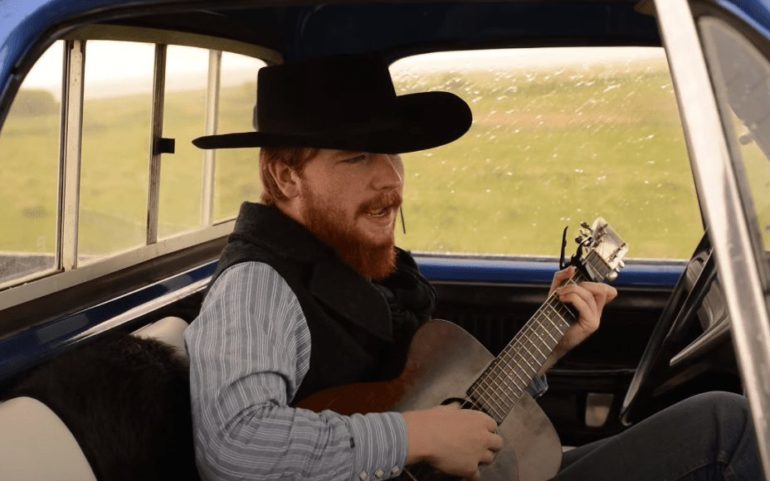 A man playing a guitar in a car