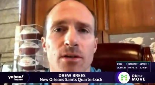 Drew Brees with a bottle of liquid in front of him