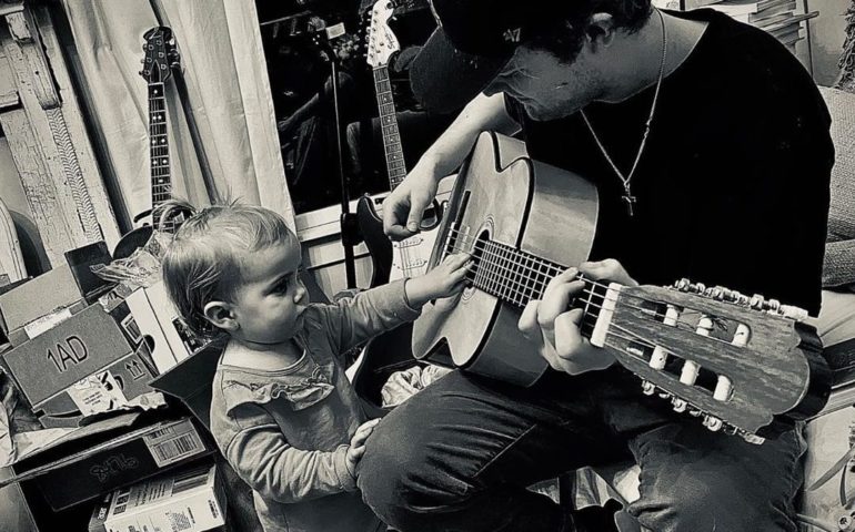 A person playing a guitar next to a child playing a guitar