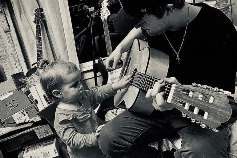 A person playing a guitar next to a child playing a guitar