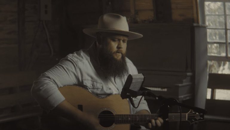 A man in a cowboy hat playing a guitar