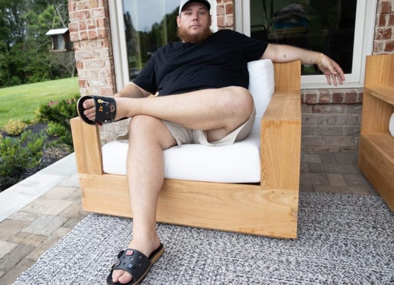 Luke Combs sitting on a white chair outside