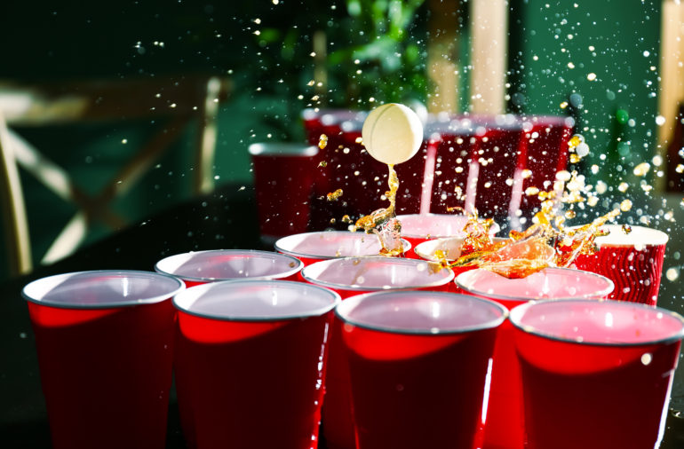 A table with red cups and red cups with red liquid in them