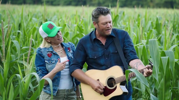 Blake Shelton and woman holding a guitar and a woman in a field