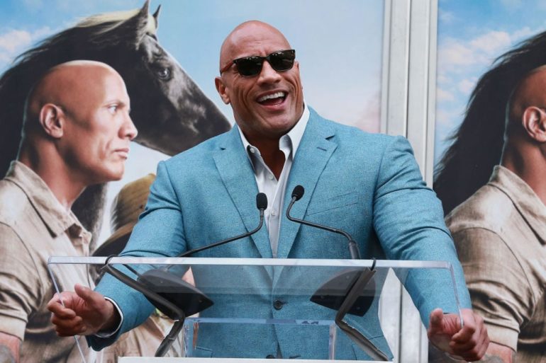 Dwayne Johnson in a suit laughing