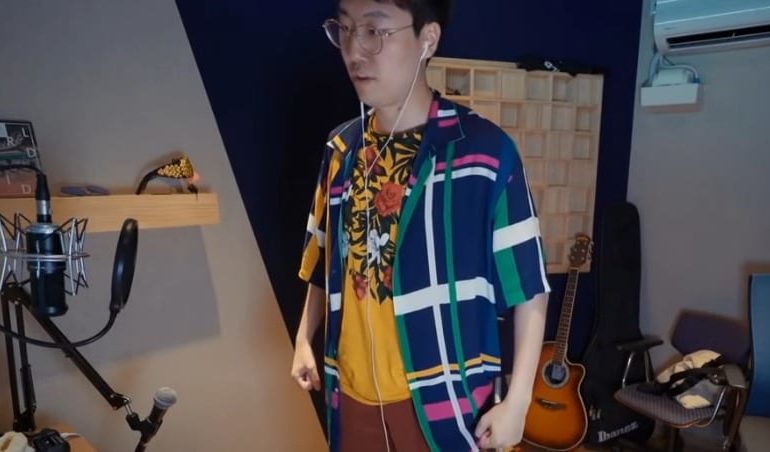 A man wearing a colorful shirt and holding a guitar