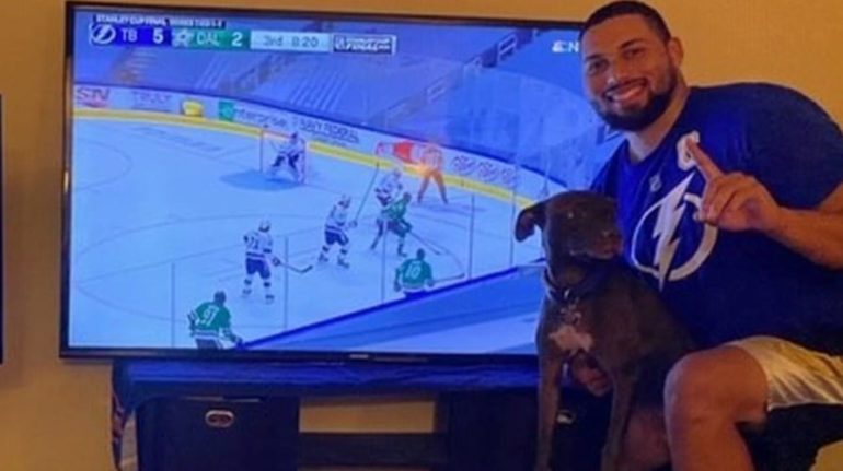 A man and a dog sitting in front of a tv
