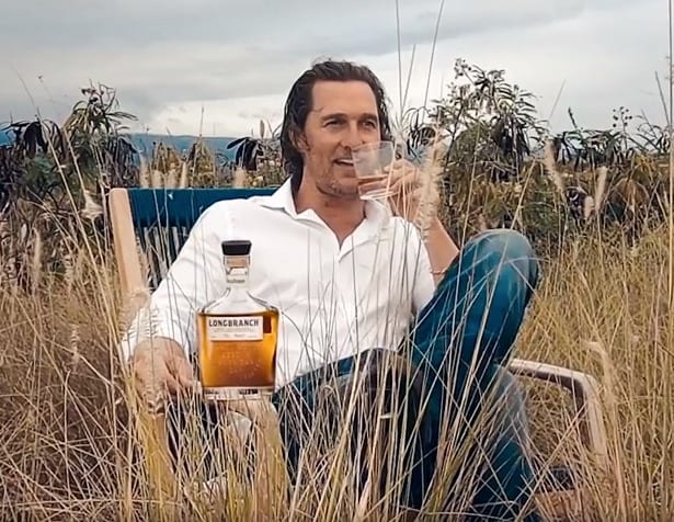Matthew McConaughey sitting in a chair with a bottle of wine in the hand