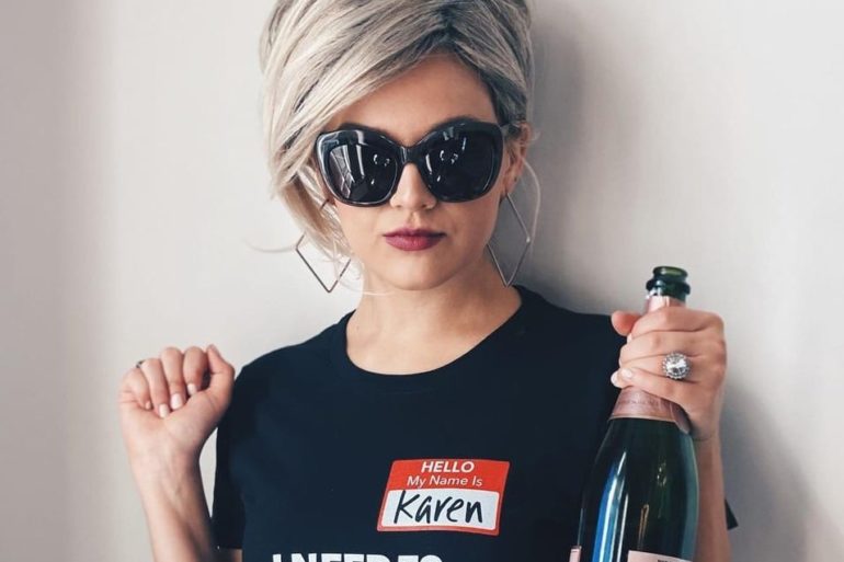 A woman wearing sunglasses holding a bottle