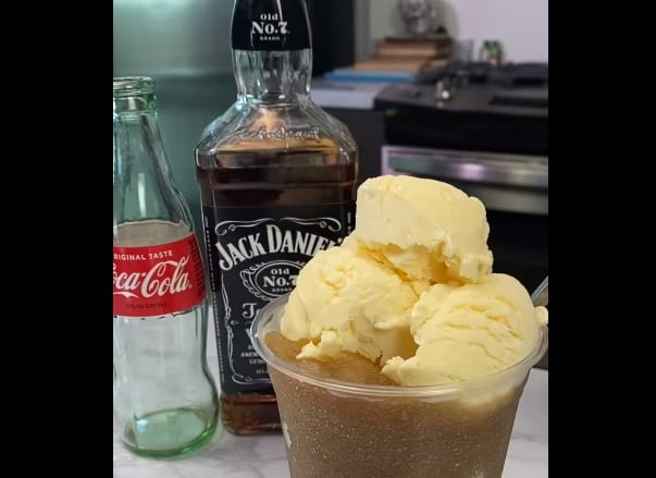 A bottle of liquor next to a glass of ice cream