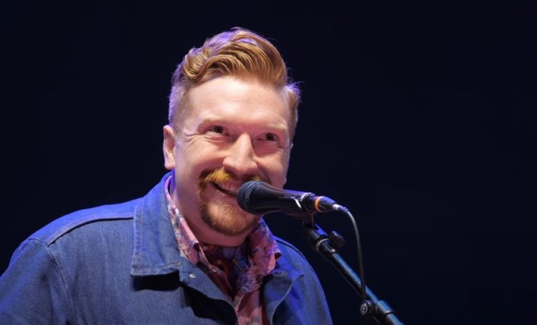A man with a mustache and a microphone in front of him
