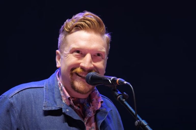 A man with a mustache and a microphone in front of him