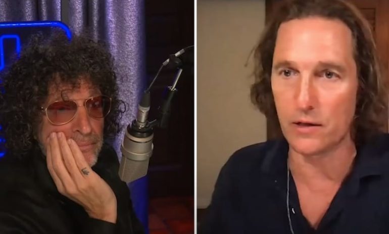 Howard Stern with the hand on the chin and a microphone in front of him