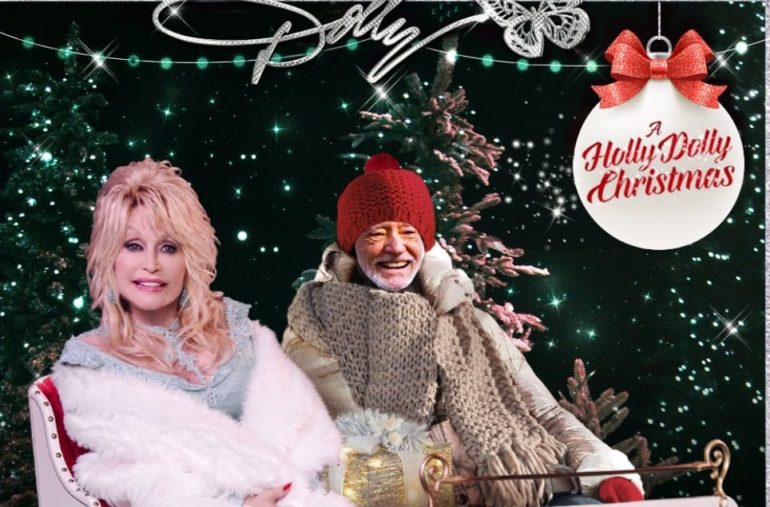 Dolly Parton and woman sitting on a sled in front of a christmas tree