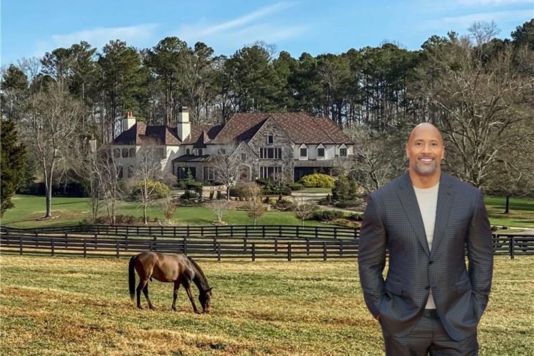 Dwayne Johnson standing in front of a horse in a fenced in pasture