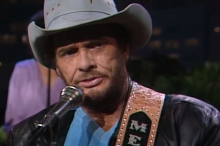 Merle Haggard wearing a hat and a microphone