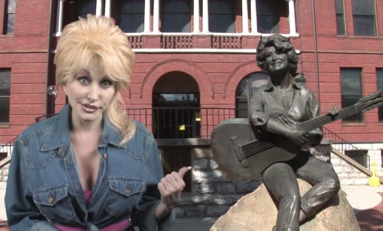 Dolly Parton standing next to a statue