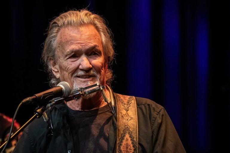 Kris Kristofferson with a beard and a microphone in front of him