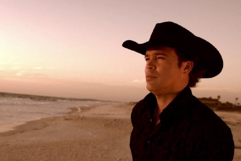 A man wearing a hat and standing on a beach