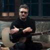Eric Church sitting on a couch holding a guitar