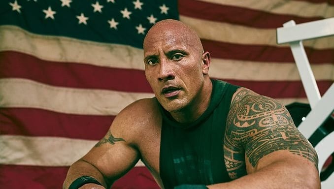 Dwayne Johnson sitting in front of a flag