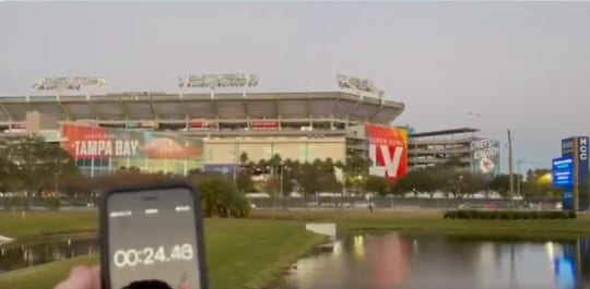 A stadium with a screen and a river in front of it