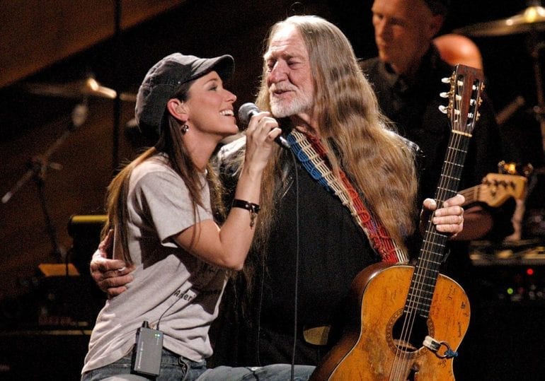 Willie Nelson and woman singing into a microphone