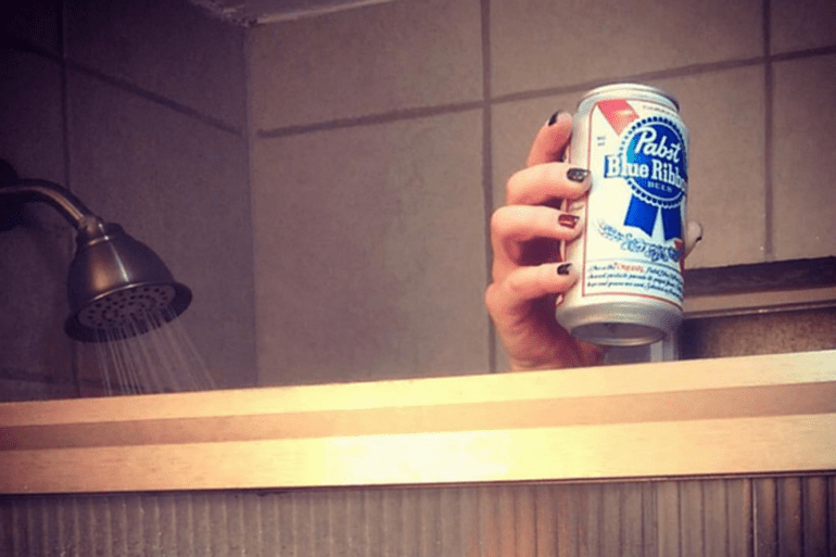 A hand holding a can of beer