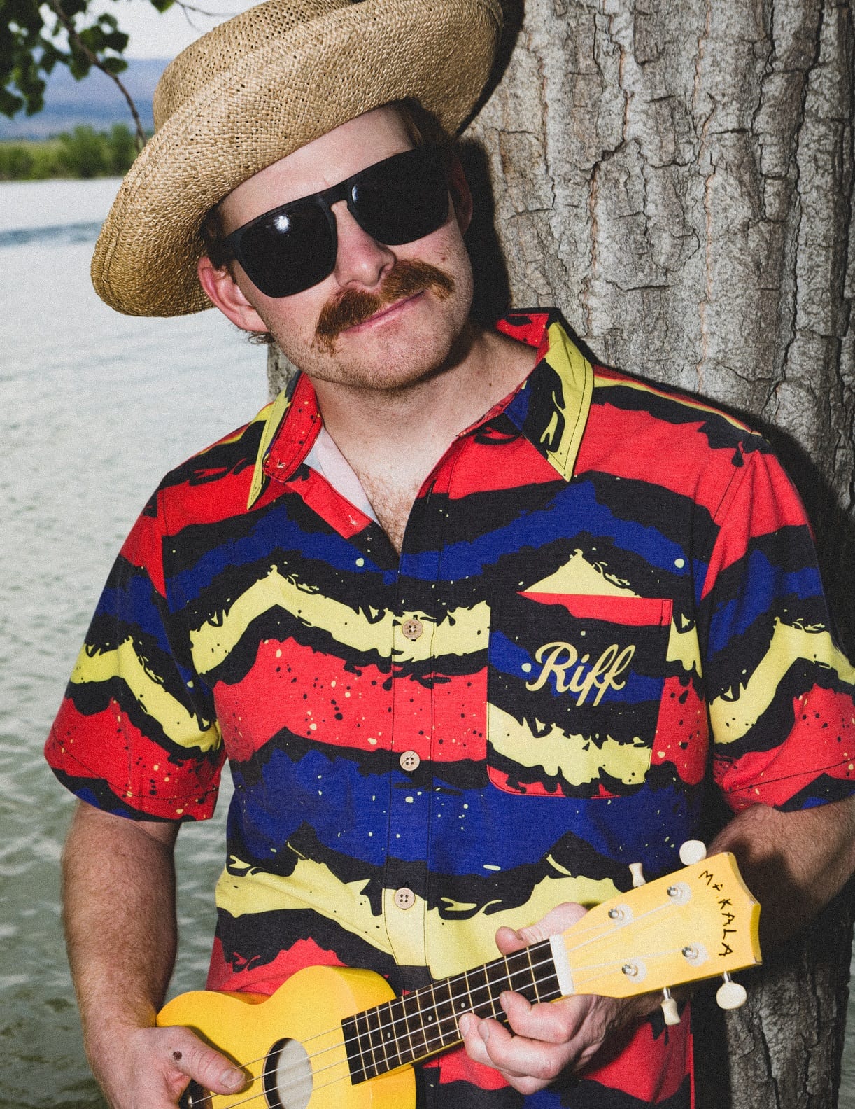 A man wearing sunglasses and a hat holding a guitar