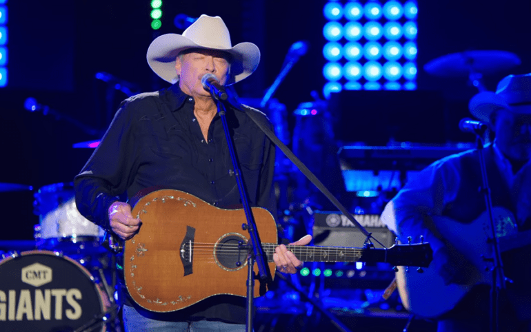 A person wearing a cowboy hat and playing a guitar on a stage