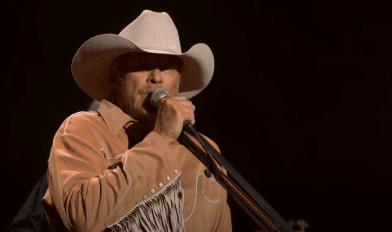 A man wearing a cowboy hat and singing into a microphone