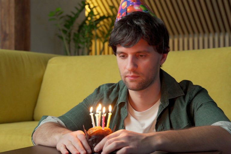 A man holding a cupcake with candles on it