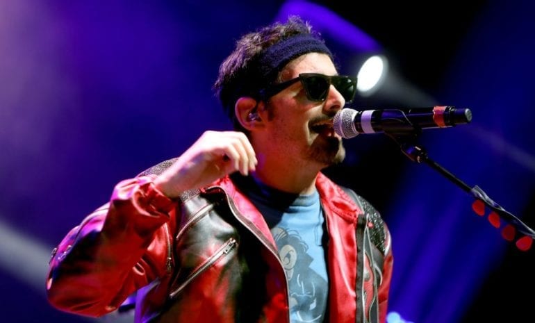 A man with sunglasses singing into a microphone