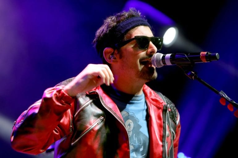 A man with sunglasses singing into a microphone