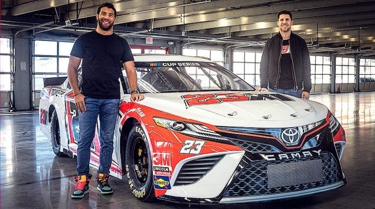A couple of men standing next to a race car