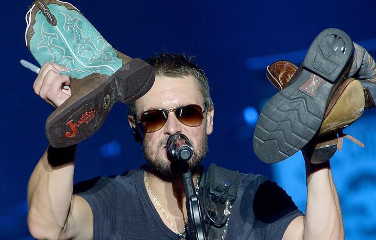 Eric Church with a mask and sunglasses holding a bottle of beer
