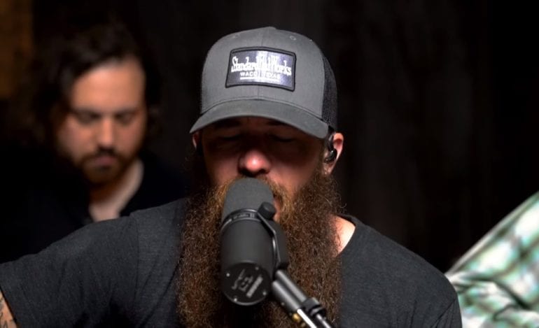 A man with a beard and a hat holding a microphone