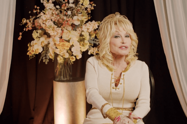 Dolly Parton in a dress holding flowers
