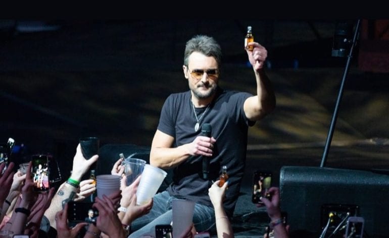 Eric Church holding a bottle and a glass of wine