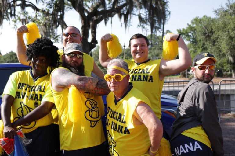 A group of people wearing yellow shirts and holding yellow cans