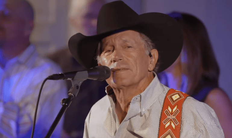 George Strait wearing a hat and a microphone