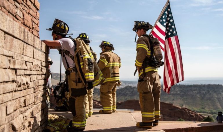 A group of firefighters standing next to a flag