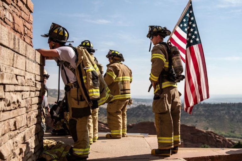A group of firefighters standing next to a flag