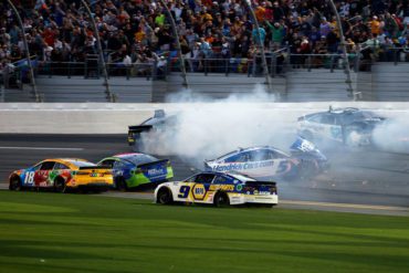 A group of race cars on a track with smoke coming out of the back of them