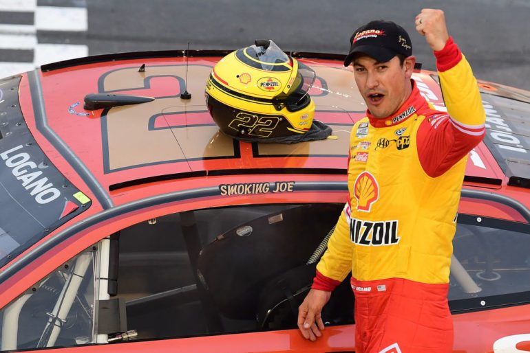 Joey Logano in a yellow and red uniform waving