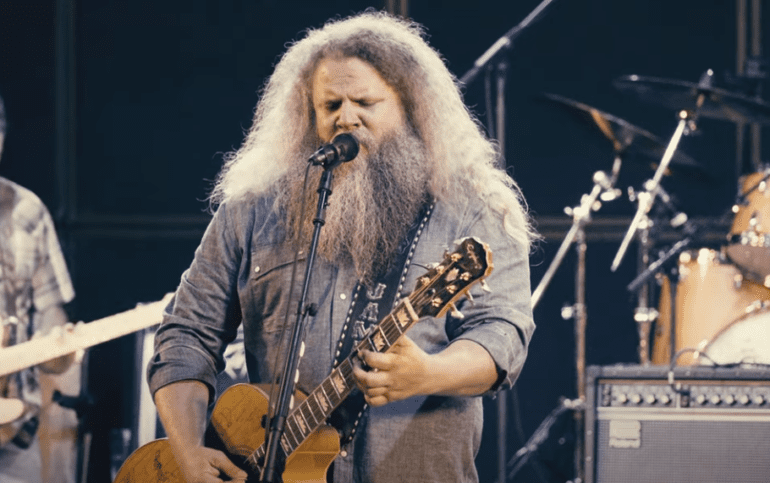 Jamey Johnson with a white beard and a long white beard playing a guitar