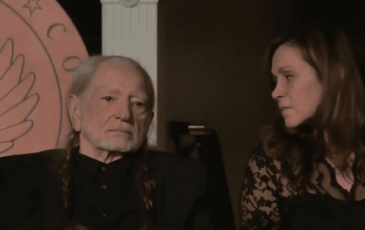 Willie Nelson and woman sitting next to each other
