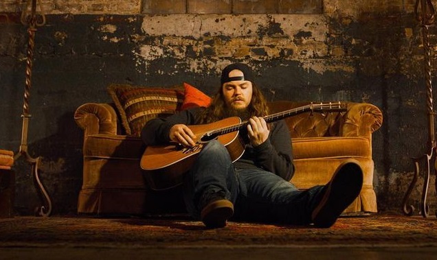 A person sitting on a couch playing a guitar