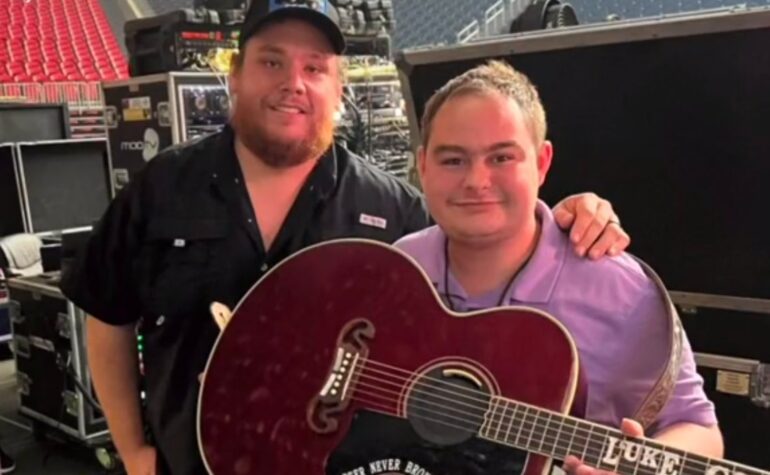 Luke Combs holding a guitar next to a man holding a guitar